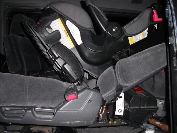 Child seat is tensioned and locked into place by seat back being raised into upright position.